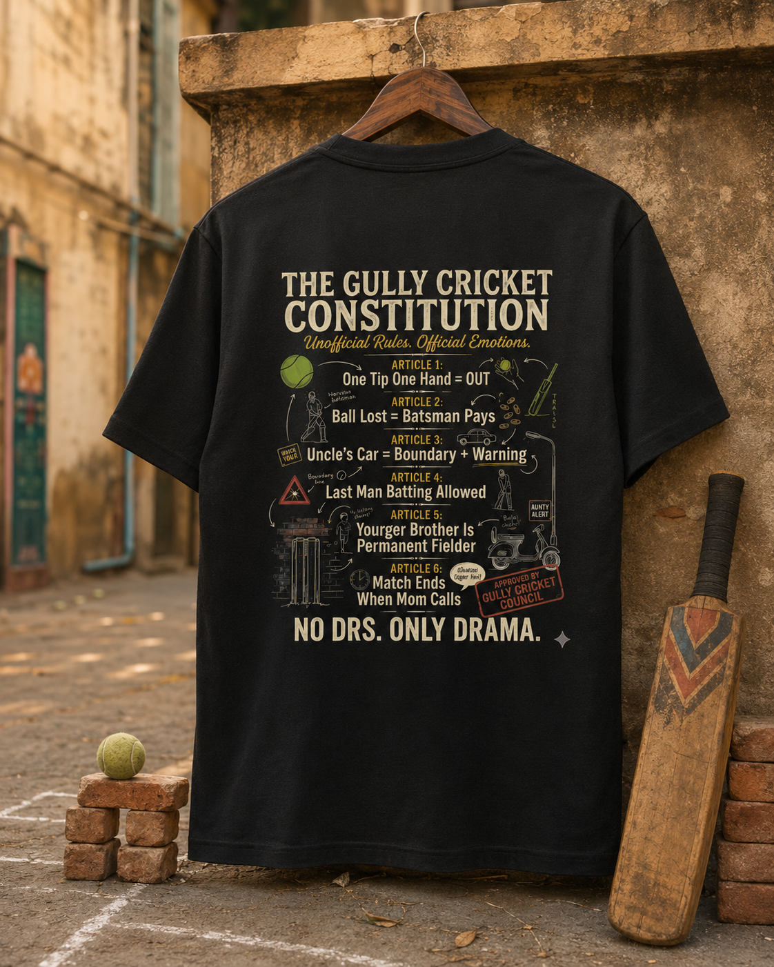 Black Gully Cricket Constitution T-Shirt hanging on a wooden hanger with cricket bat, tennis ball, and brick stumps.